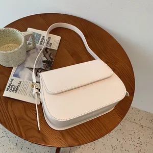 Close-up of elegant white saddle bag with golden buckle on a wooden table setup