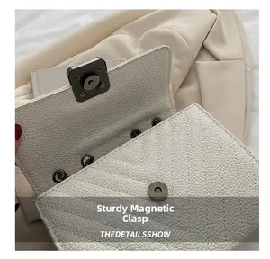 Close-up of a durable magnetic snap closure on a beige quilted leather shoulder bag