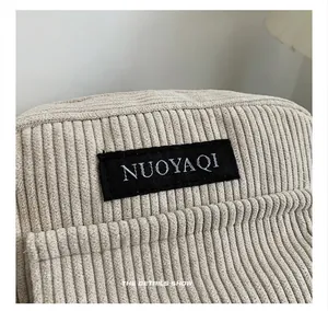 Macro view of corduroy fabric texture and rectangular logo tag on casual shoulder bag