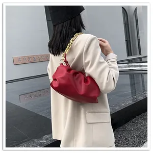 Detailed view of red cloud pleated leather crossbody bag with a chunky gold chain strap