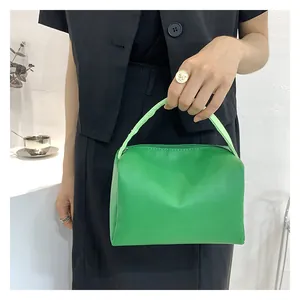 Close-up of vibrant green PU leather small square bag with smooth texture and top zipper