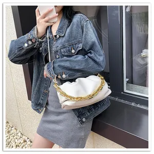 Detail of white cloud bag featuring pleated texture and chunky gold chain strap accent