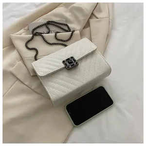 Detail of cream flap crossbody bag with V-quilted texture and metal chain strap