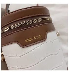 Detail der zweifarbigen Zylindertasche aus braunem Leder und weißer Krokoprägung