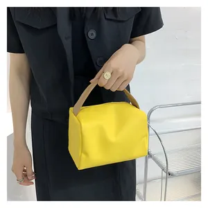 Detail of trendy bright yellow small square handbag with contrasting brown handle straps