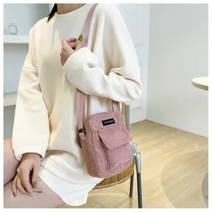 Detail view of pink corduroy crossbody bag with adjustable strap and front pocket flap