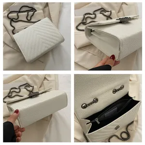Detail view of white quilted crossbody bag with metal chain strap and interior compartments