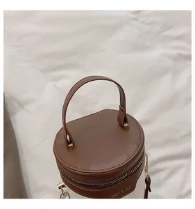 Detaillierte Draufsicht einer Zylindertasche mit weißer Krokoprägung und braunem Lederbesatz