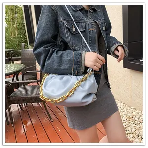 Detail of light blue pleated cloud bag with chunky gold chain and leather strap
