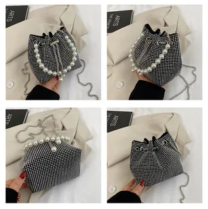 Detail view of black drawstring bucket bag with silver rhinestones and pearl handle