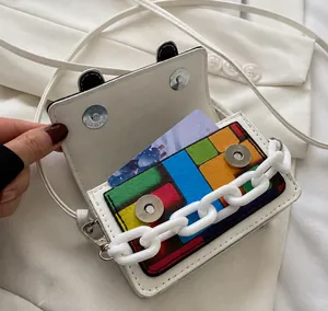 Detailed view of white mini leather bag with colorful block pocket and plastic chain