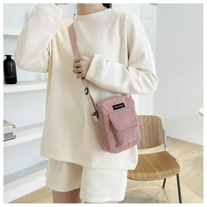Detail of pink corduroy shoulder bag showing flip-top front pocket and ribbed texture