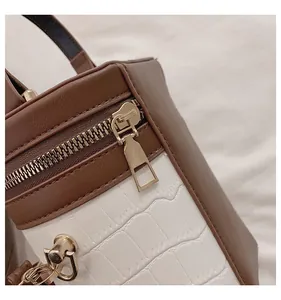 Detail der Krokodil-Lederprägung und goldener Reißverschluss an der Kontrast-Tasche