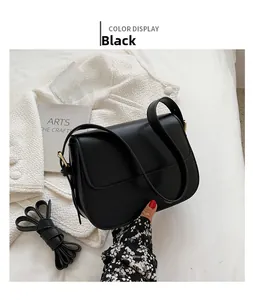 Detail view of black leather saddle bag with gold metal hardware on white fabric