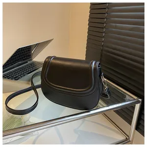 Detail of matte black faux leather shoulder bag on a minimalist glass display desk