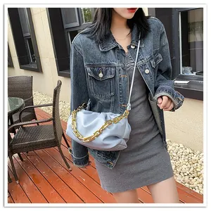Light blue pleated cloud bag with chunky gold chain strap shown on person outdoors