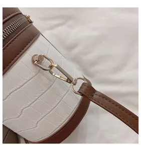 Detail aus Leder mit Krokodilprägung und goldenem Reißverschluss an zylindrischer Tasche