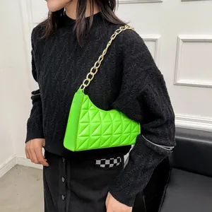 Lime green quilted shoulder bag with chunky gold chain strap worn by a model
