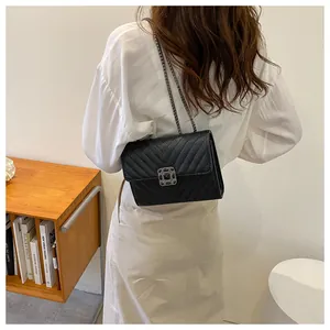 Detail of black chevron quilted leather bag with dark grey metal buckle and chain strap