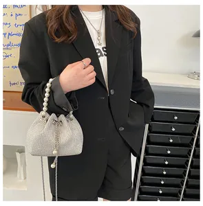 Detail of silver bucket bag with rhinestones, pearl handle and metal chain drawstring