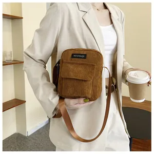 Detailed texture of brown corduroy crossbody bag with front flap pocket and adjustable strap
