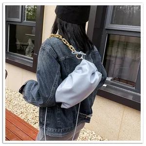 Detail of light blue pleated cloud bag with chunky gold chain strap on shoulder