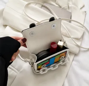 Mini crossbody bag showing internal capacity with lipsticks and a powder compact
