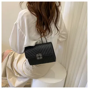 Detail of black chevron quilted leather crossbody bag with silver hardware on model