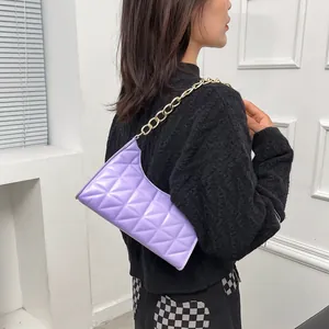 Purple quilted baguette bag with thick gold chain strap worn by a female model