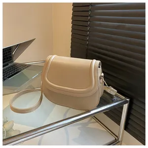 Detail of beige faux leather saddle bag on glass shelf with minimal background