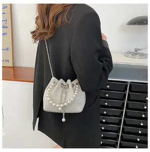 Detail of silver rhinestone bucket bag with large pearl handle and metal chain strap