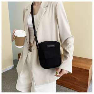 Detail of black corduroy crossbody bag with adjustable strap on a female model