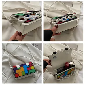 Detail view of mini white crossbody bag with pixel patterns and gold chain accents