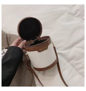 Detail der weiß-braunen Zylindertasche mit Krokodilmuster und praktischem Reißverschluss