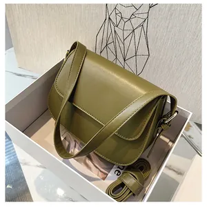 Close-up of olive green saddle bag in gift box with gold metal strap buckle
