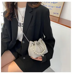 Close-up of silver rhinestone bucket bag with pearl handle and metal chain detail