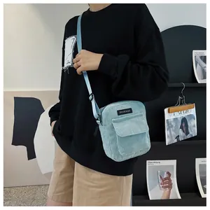 Fashionable light blue corduroy crossbody bag worn by a model in a minimalist setting