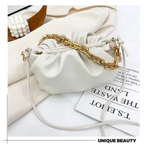 Detail of white pleated cloud bag with chunky gold chain handle and soft leather texture