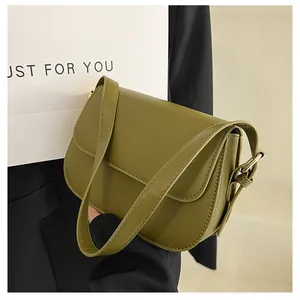 Detailed view of matte green leather saddle bag with gold adjustment buckle and flap closure