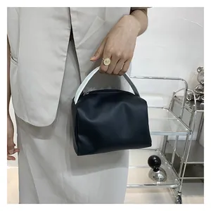 Detail view of small black and white contrast top handle bag with modern boxy design