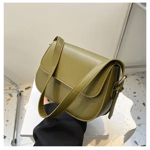 Detail of olive green faux leather saddle bag with adjustable strap and metal hardware