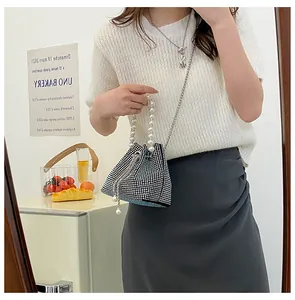 Chic silver rhinestone bucket bag with pearl handle and metal chain on a female model