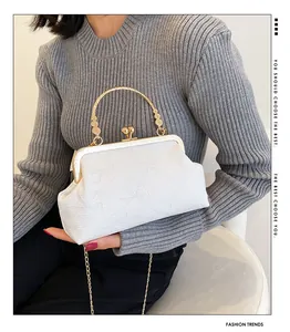 Detail of cream vintage evening bag with embossed bow texture and gold clasp handle