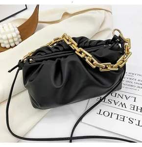 Detail of black pleated cloud bag with chunky gold chain strap and soft leather texture