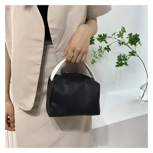 Close-up of a stylish black and white contrast handbag with top handle and metal zipper