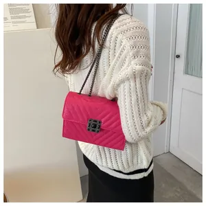 Detail of fuchsia crossbody bag with V-quilted pattern and gemstone lock buckle
