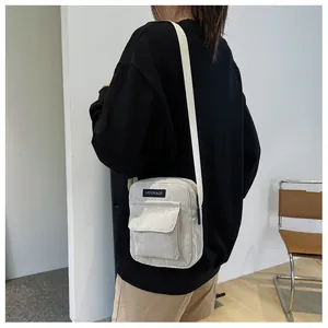 Detail of off-white corduroy crossbody bag showing front flap pocket and adjustable strap