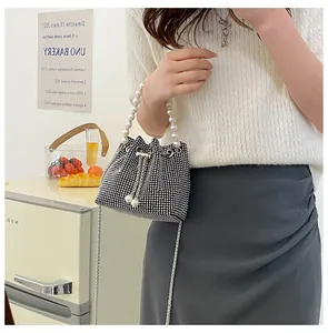 Detail of a sparkling rhinestone bucket bag with large pearl handle and silver chain strap