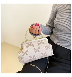 Close-up of cream textured fabric handbag with bow print and floral metal handle