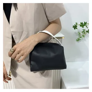 Detail of a black matte handbag with contrast white handle and smooth zipper closure